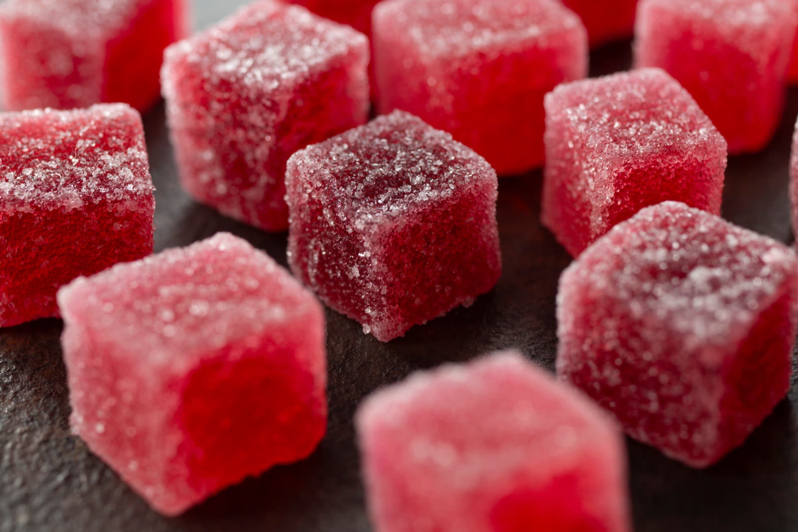 Sugar-dusted red candy cubes on a dark surface