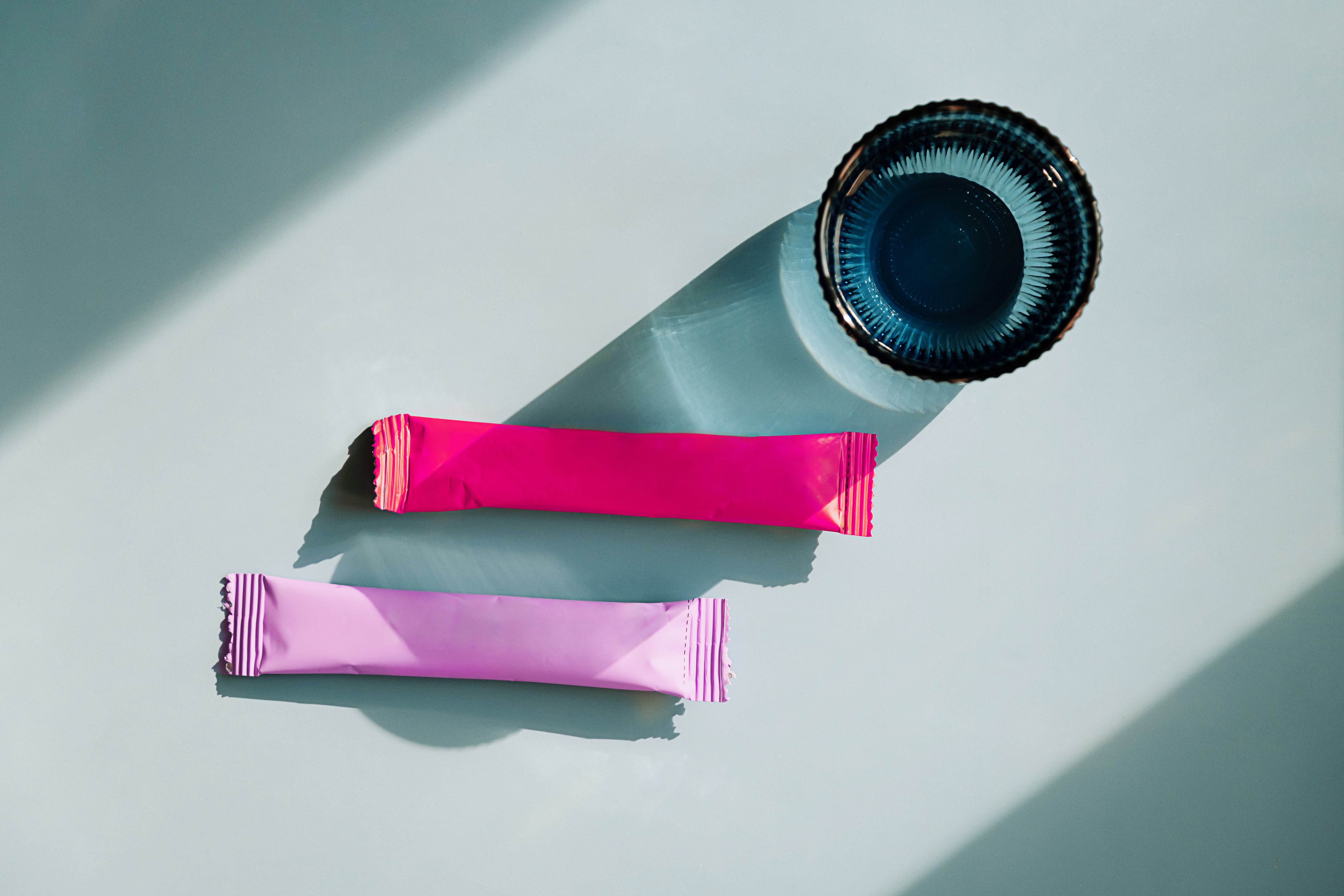 Bright stick packs and container on teal background